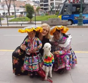 Linda Khanna with two women in traditional dress and a baby llama